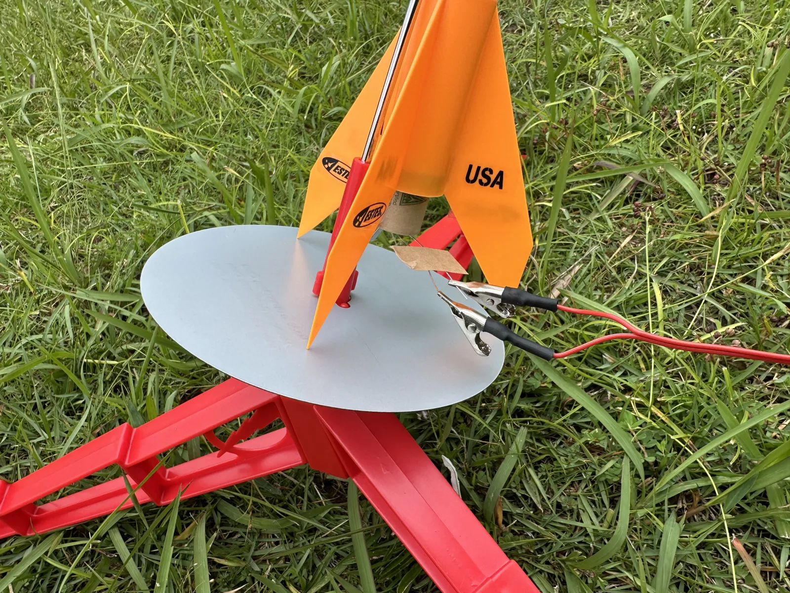 発射台にセットされたオレンジ色のモデルロケットと、点火クリップのクローズアップ