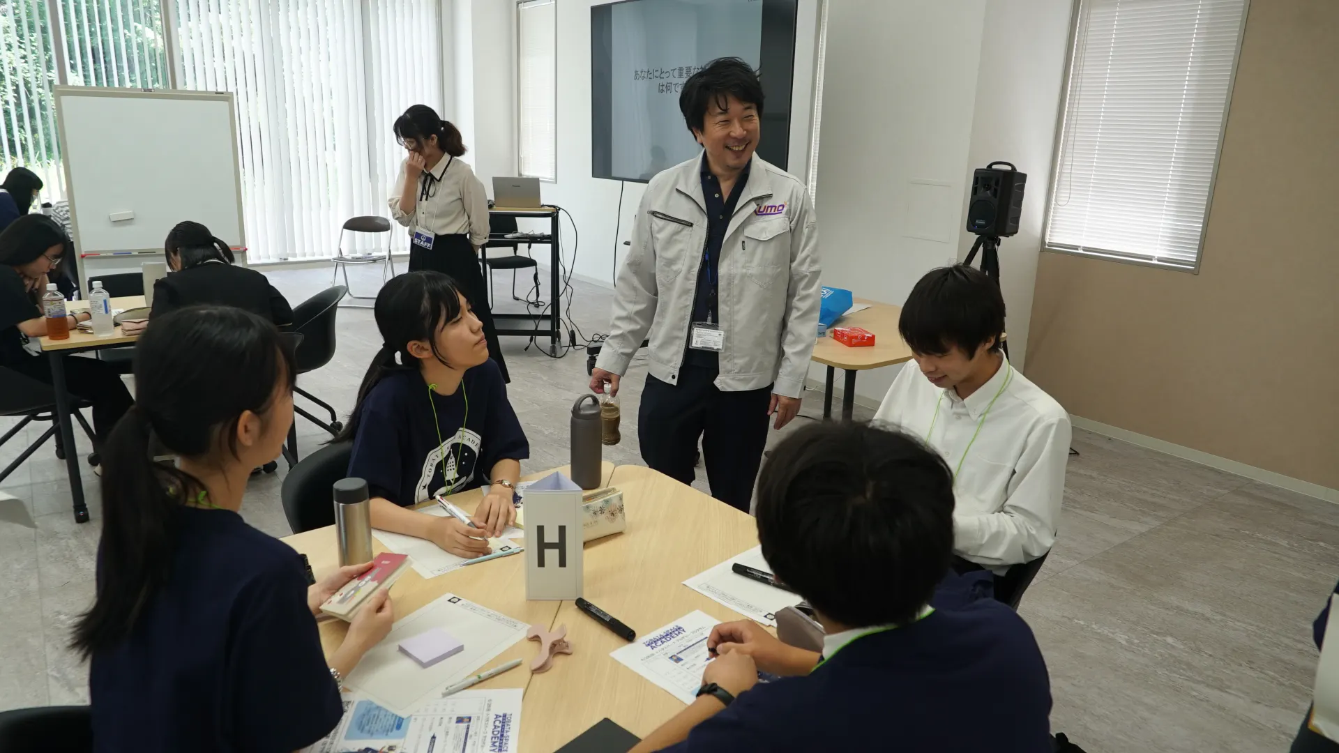チームHのテーブルに加わって意見交換する布施先生とアカデミー生たち