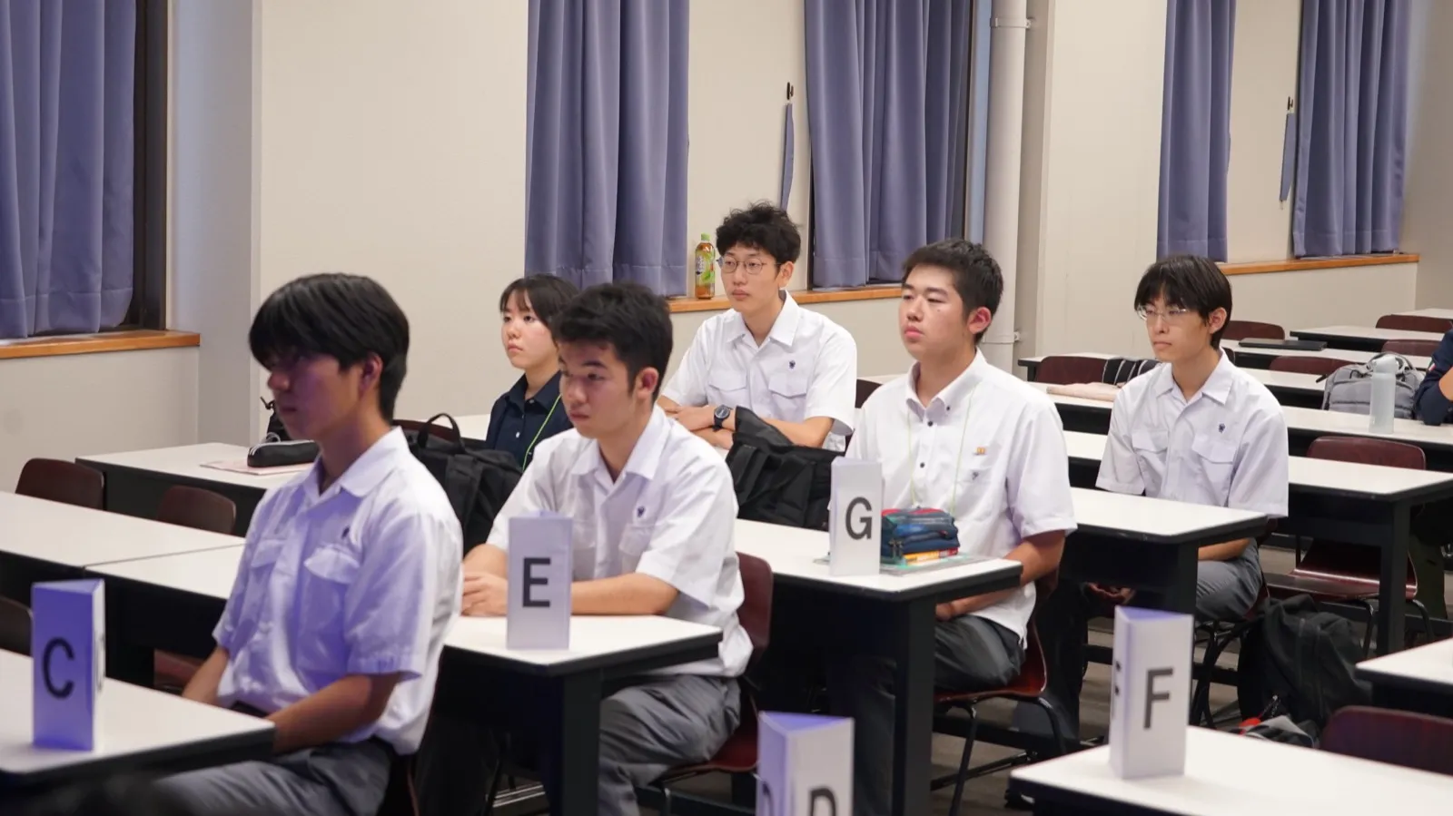 チームごとの札が置かれた机に着席し、話を聞くアカデミー生たち
