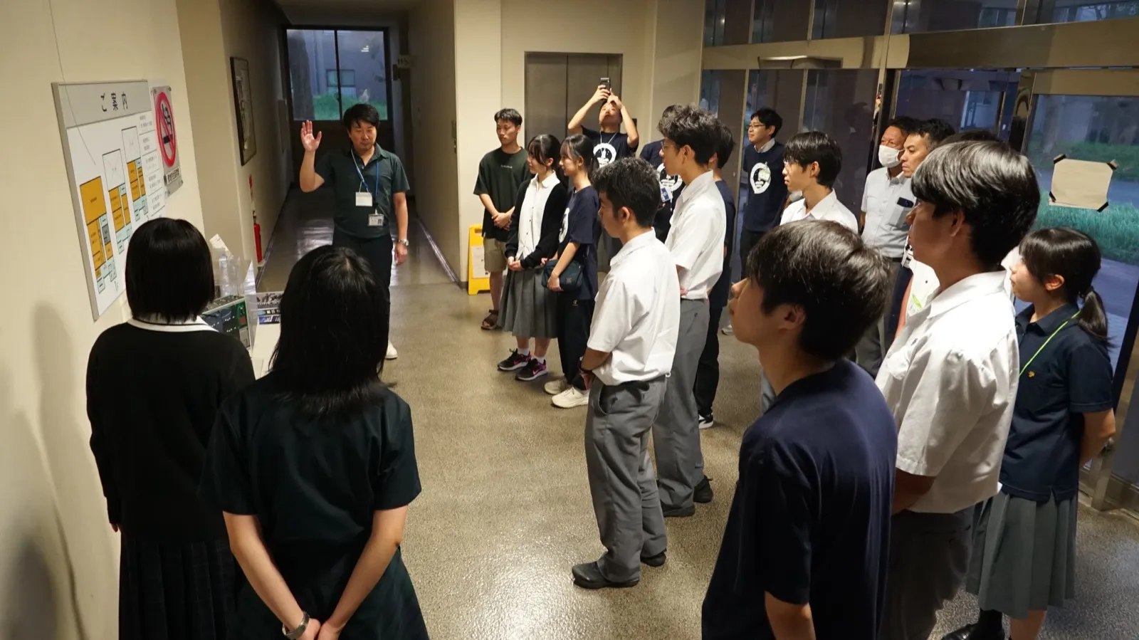 廊下に集まり、見学前の説明を聞くアカデミー生たち