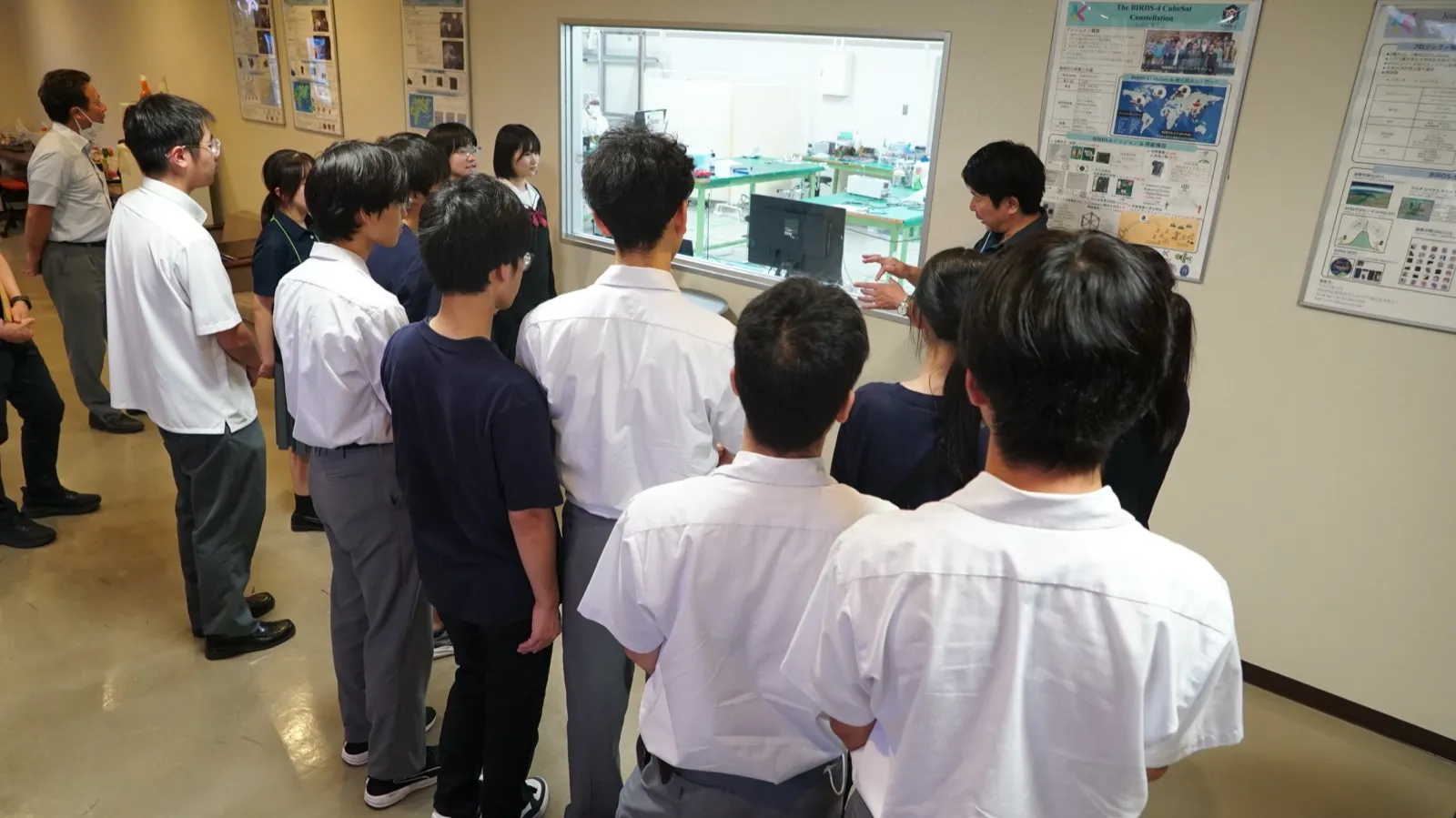 ガラス窓越しに試験室の中をのぞき込むアカデミー生たち
